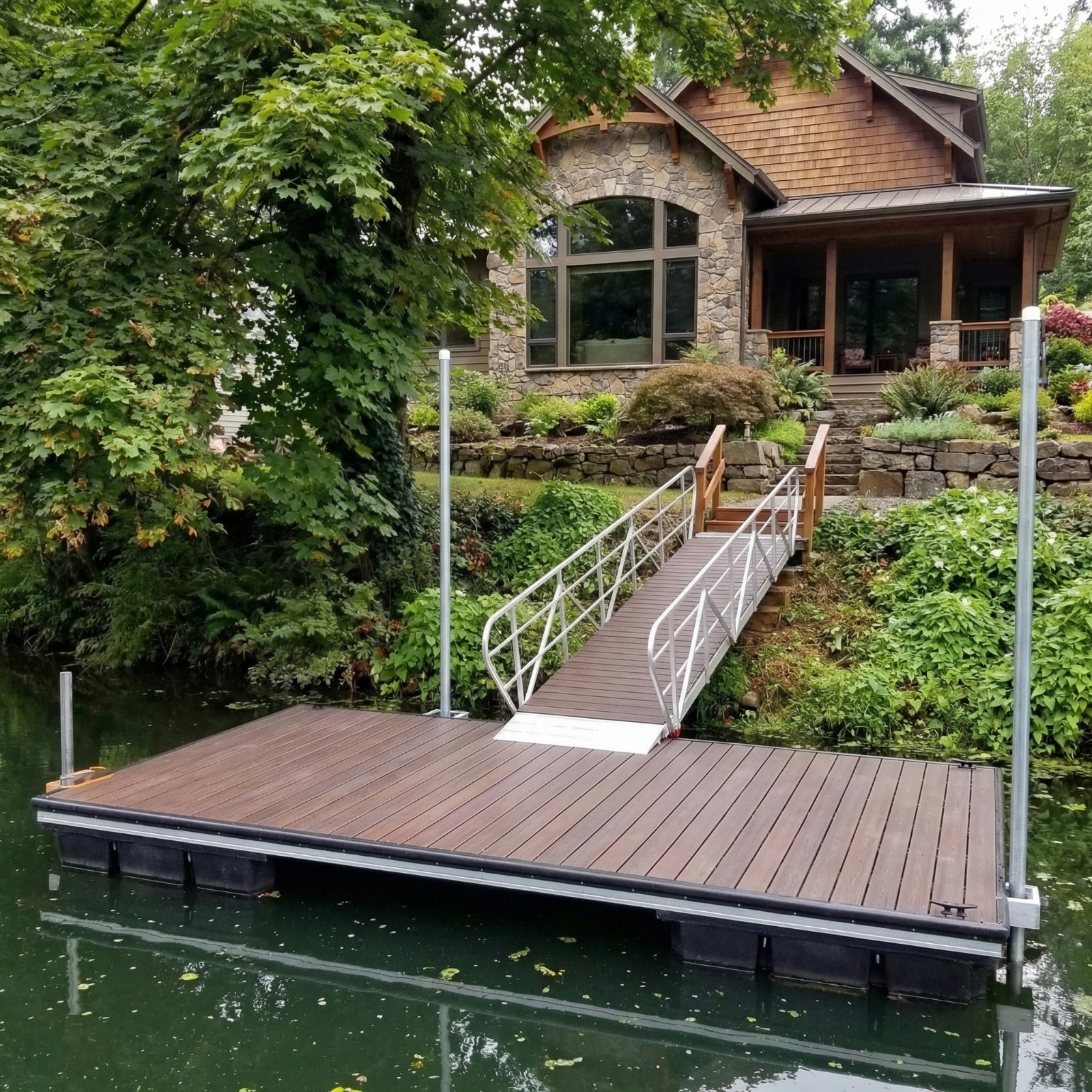 Aluminum floating dock with brown WPC decking and black square floats — stone craftsman home
